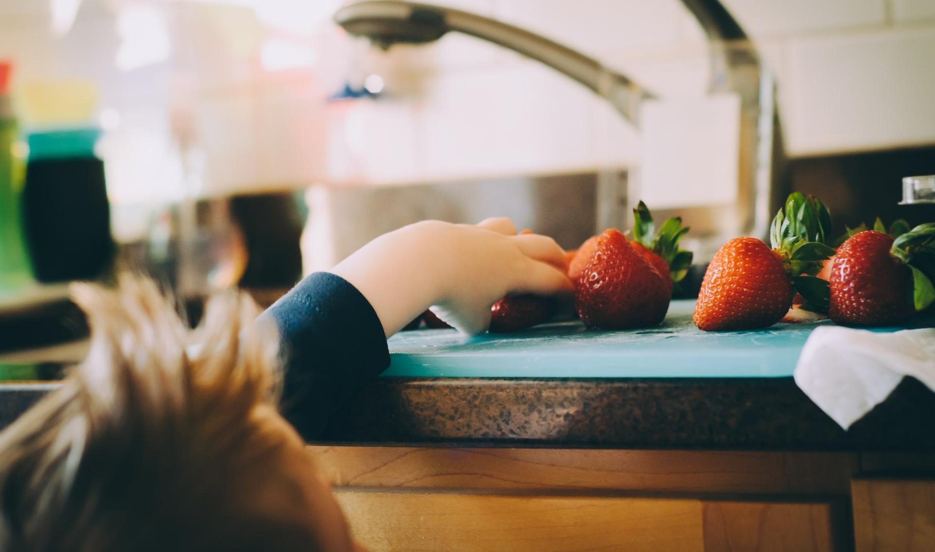 child picking strawberries in kitchen